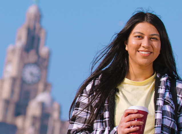 Smiling student standing in front of liver building